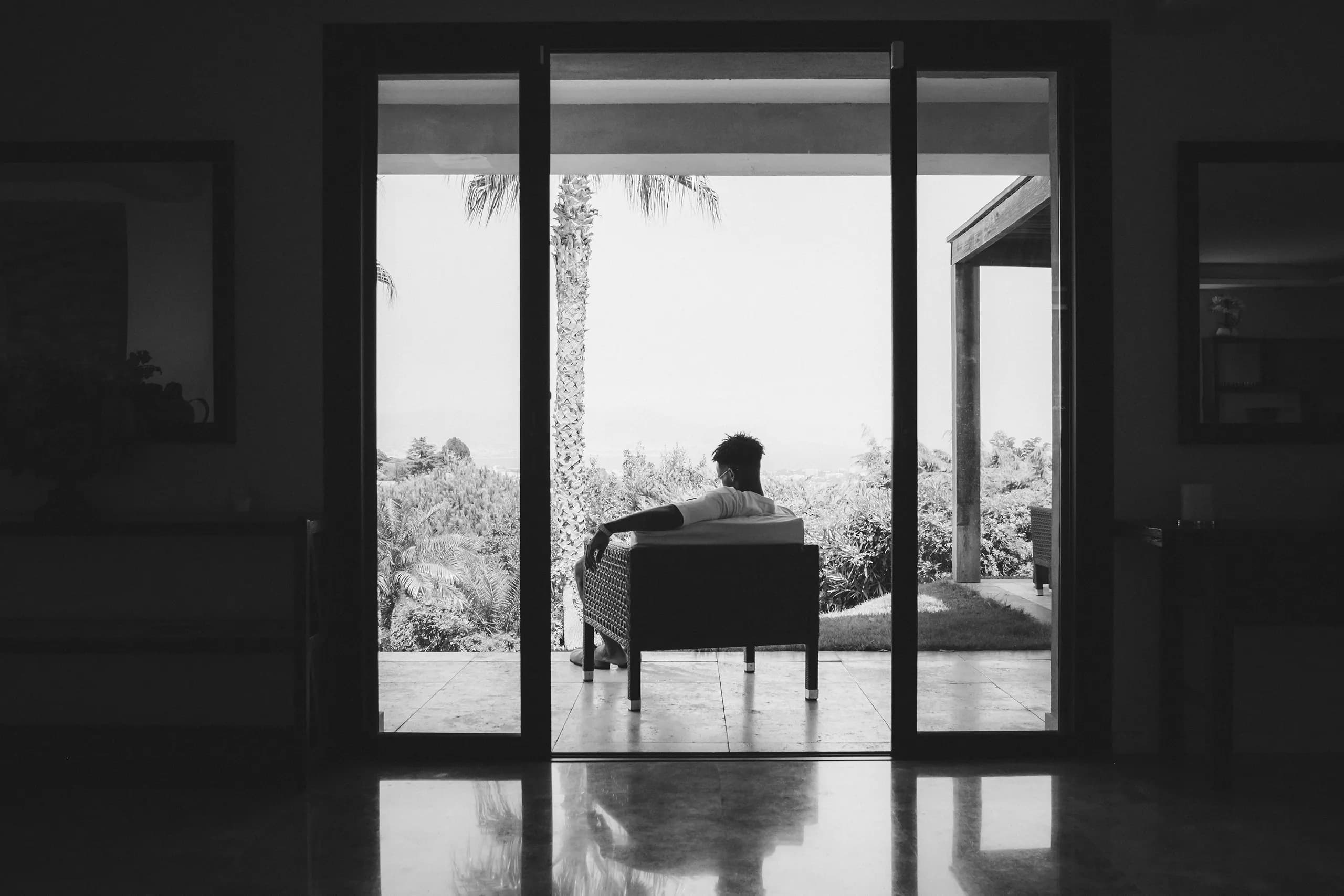 Homme assis face au jardin d'une maison contemporaine